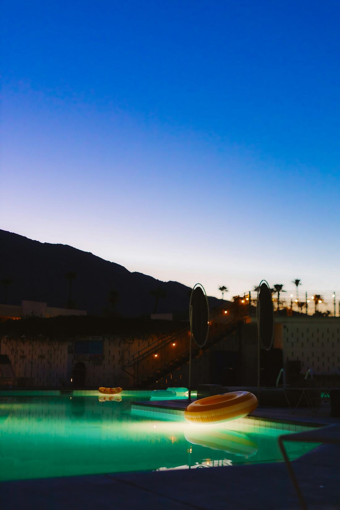 The remodelled pool lit at night, mountains in silhouette